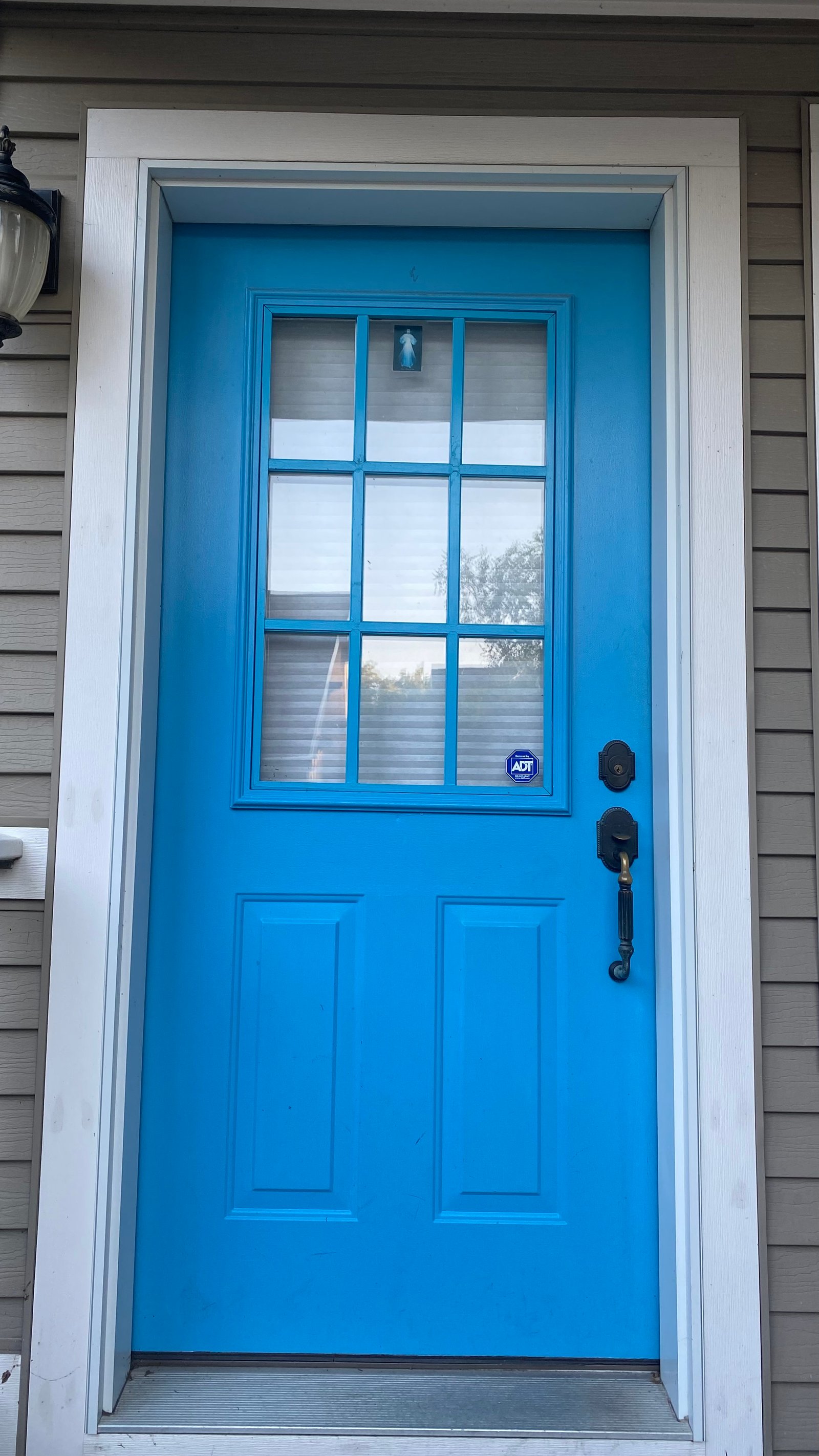 After, daytime close-up: white storm door installed over the blue entry door