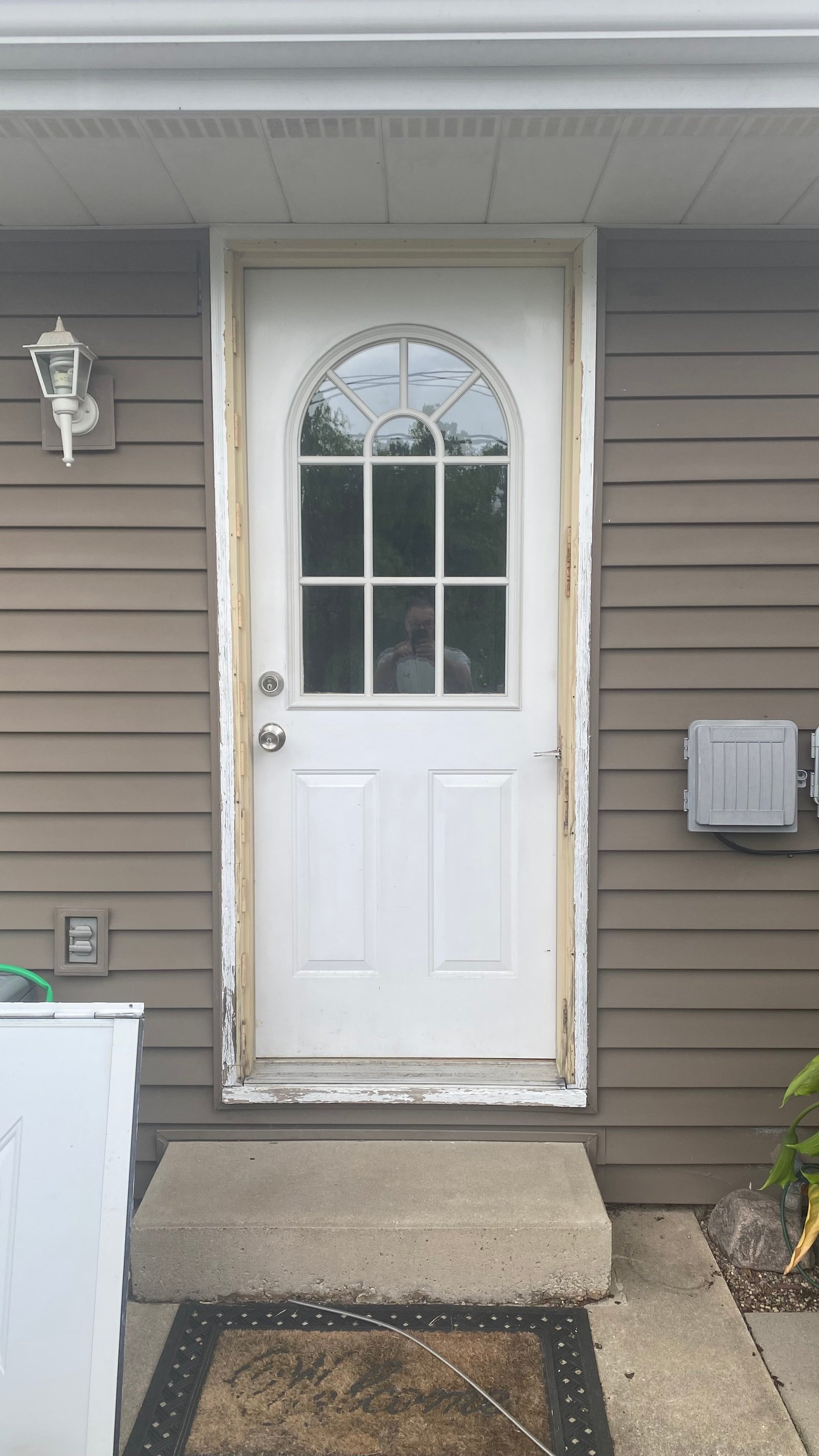Before: white entry door with arched window, no storm door installed
