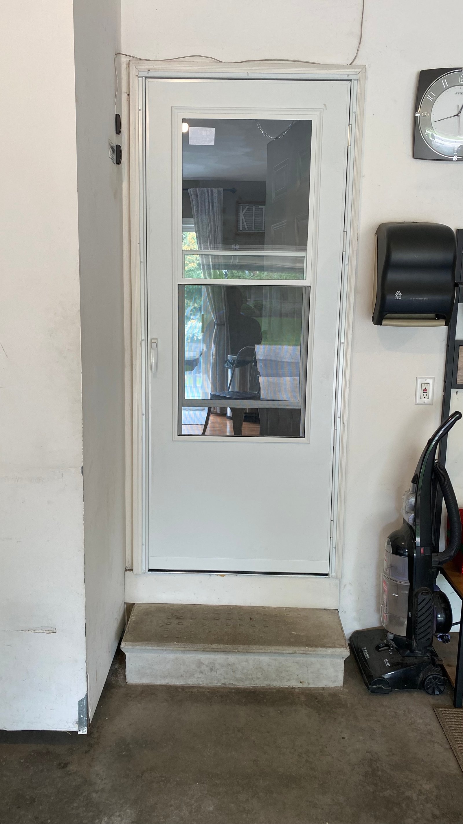 Interior garage view of the installed white storm door with glass and screen
