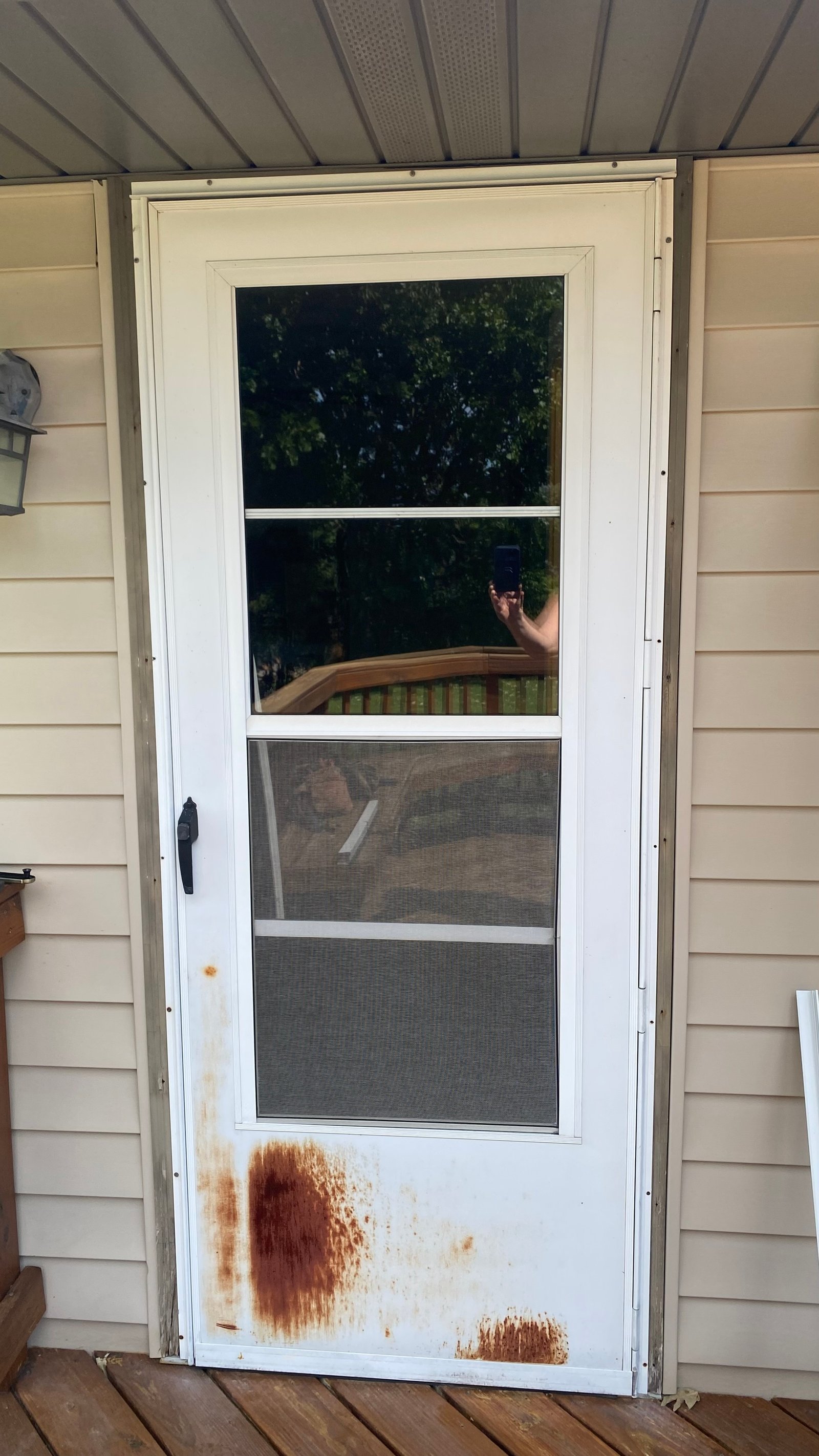 Before: old white storm door with heavy rust staining on the lower panel